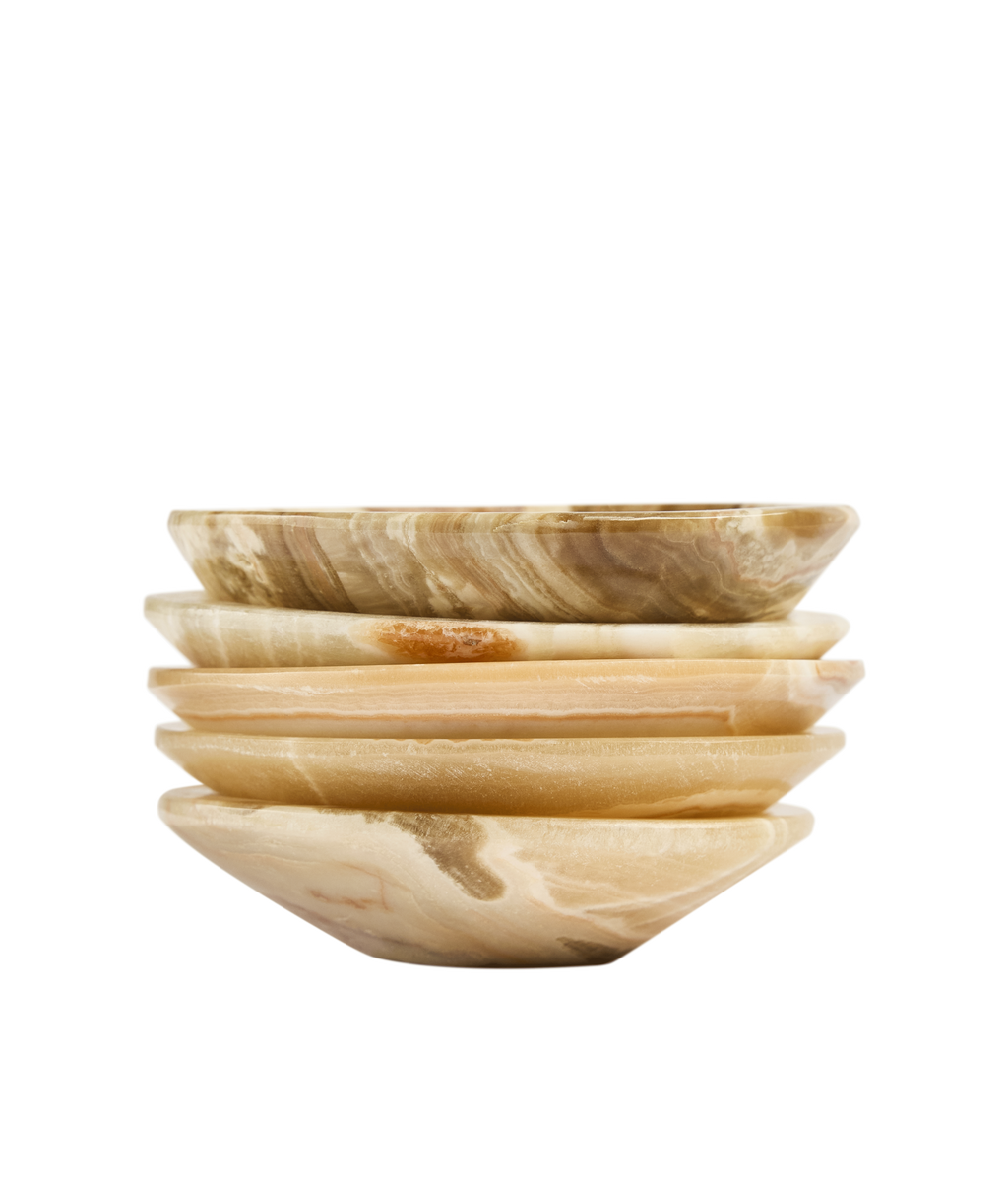 Stack of five aragonite ritual bowls seen from the side, with light and amber veins