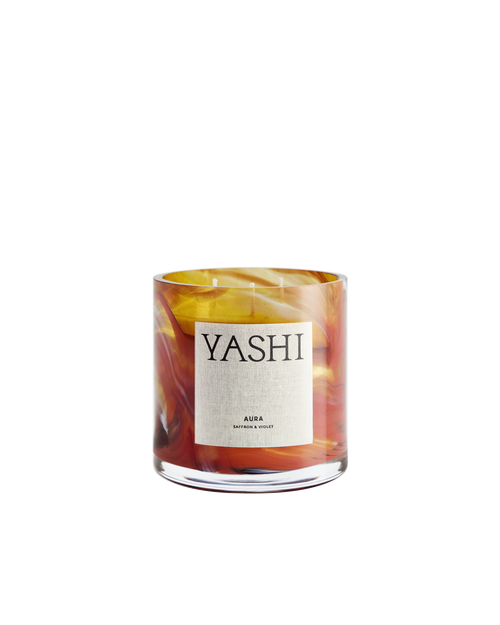 Bougie Aura Yashi en verre soufflé aux volutes orange, rouges et ambrées, étiquette crème, sur fond clair